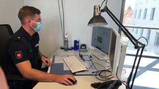 Ein Polizist sitzt vor einem Rechner. Dienststellen aus ganz Deutschland beteiligen sich an der Aktion #Polizei110.