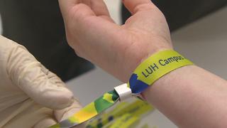Einer Studentin an der Leibniz Universität Hannover wird ein Armband als Impfnachweis angelegt.