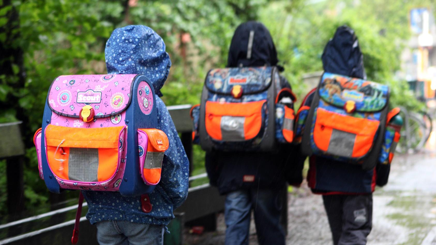  19.05.2010, Berlin, Deutschland - Kinder bei Regenwetter auf dem Weg zur Schule. QF, Rückansicht, Schüler, Grundschüler, Rücken, Haltungsschäden, Nässe, europäisch 00S100519D004.JPG MODEL RELEASE: NO, PROPERTY RELEASE: NO MR:N