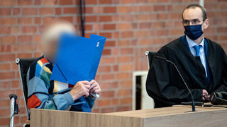 07.10.2021, Brandenburg, Brandenburg/Havel: Der angeklagte ehemalige KZ-Wachmann sitzt mit seinem Anwalt Stefan Waterkamp im Gerichtssaal. Der inzwischen 100-jährige Angeklagte soll zwischen 1942 und 1945 im Konzentrationslager Sachsenhausen nahe Berlin wissentlich und willentlich Hilfe zur Ermordung von Lagerinsassen geleistet haben, heißt es in der Anklage. Es gehe um Beihilfe zum Mord in 3518 Fällen. Foto: Fabian Sommer/dpa - ACHTUNG: Der Angeklagte wurde auf Anordnung des Gerichts aus rechtlichen Gründen gepixelt +++ dpa-Bildfunk +++