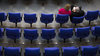 Zwei Abgeordnete sitzen in den leeren Sitzreihen im Deutschen Bundestag in Berlin, 28.02.2018.