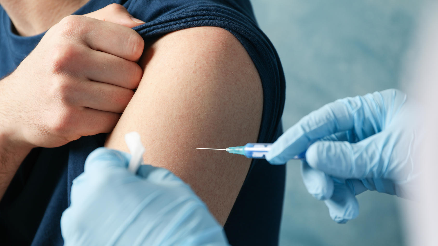Ein Patient erhält per Spritze eine Impfung in den Oberarm.