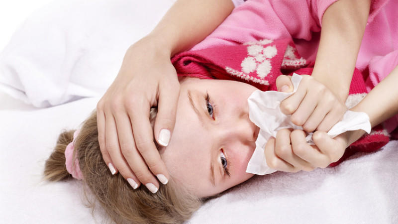 Sick little girl with handkerchief in bed.