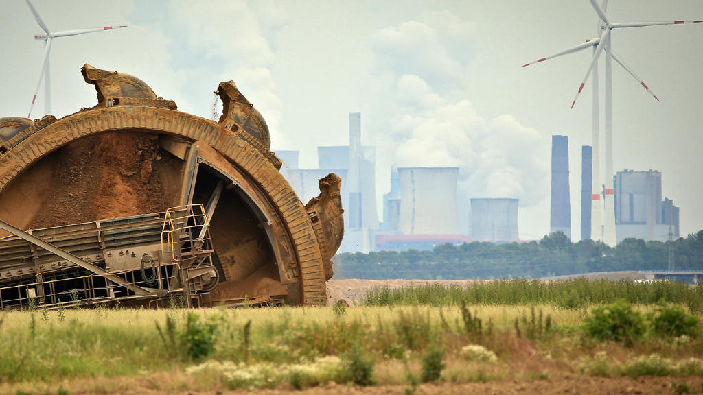ARCHIV - 20.06.2019, Nordrhein-Westfalen, Jackerath: Der Schaufel eines Braunkohlebaggers baggert im Tagebau Garzeiler; im Hintergrund stehen eines der RWE-Kraftwerke und daneben Windräder. (zu dpa Themenpaket Weltklimakonferenz COP26 in Glasgow) Fot