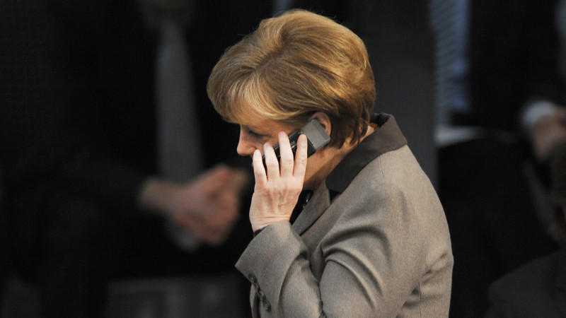 ARCHIV - Mit einem Handy am Ohr geht Bundeskanzlerin Angela Merkel (CDU) am 29.03.2012 durch den Plenarsaal des Bundestages in Berlin. Foto: Rainer Jensen/dpa (zu dpa «Themenpaket zum 1. Jahrestag der ersten Snowden-Enthüllungen» vom 01.06.2014) +++(