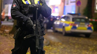 14.11.2021, Hamburg: Ein Polizist mit einer Maschinenpistole sichert einen abgesperrten Tatort. In Hamburg-Harburg sind am Sonntagnachmittag Schüsse gemeldet worden. Zwei Menschen seien möglicherweise verletzt, sagte ein Beamter beim Lagedienst der Polizei. Foto: Jonas Walzberg/dpa +++ dpa-Bildfunk +++