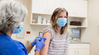 Eine ältere Ärztin bzw. Krankenschwester impft eine Frau.