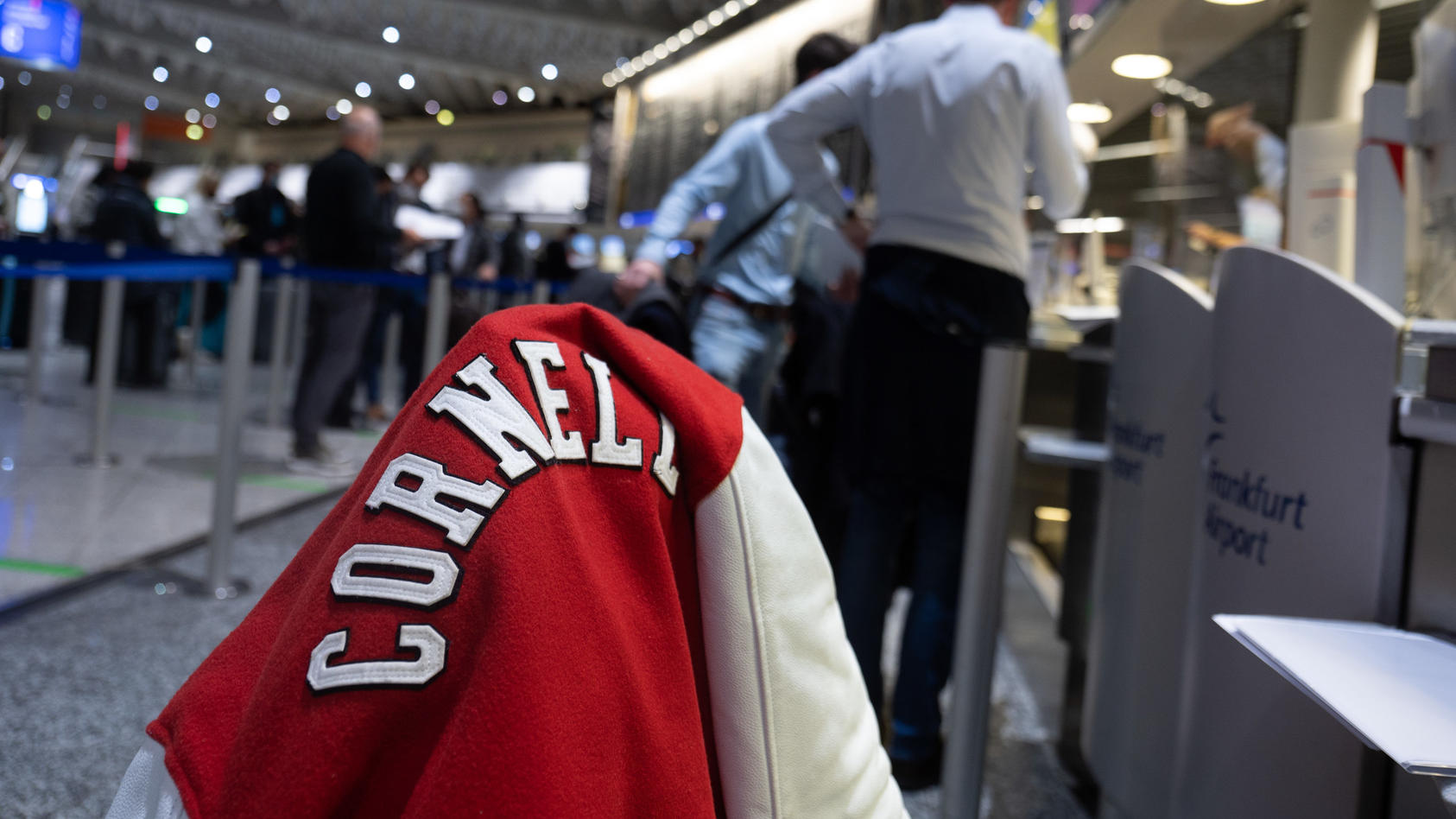 Eine Jacke mit dem Schriftzug der Universität Cornell aus dem US-Bundesstaat New York hängt auf einem Koffer, der auf dem Flughafen Frankfurt, am Check-In von Singapore Airlines für einen Flug nach New York. Ab dem