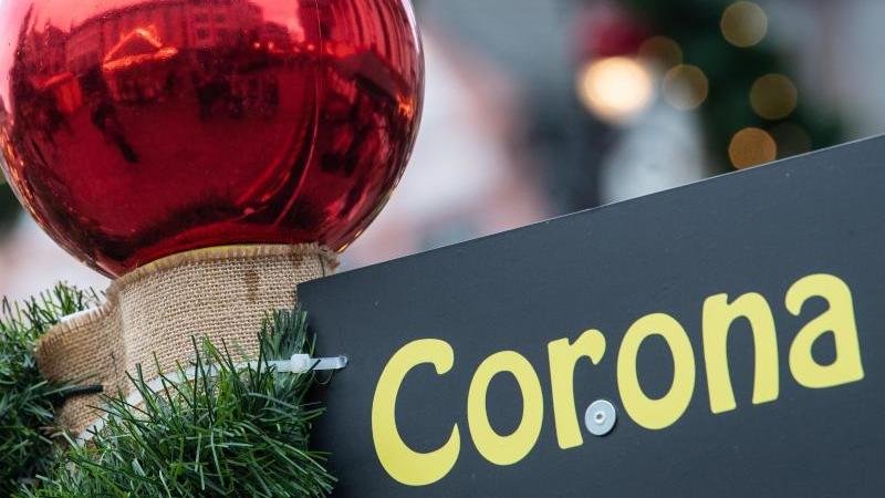 „Corona“ steht auf einem Hinweisschild an einem Verkaufsstand auf dem Weihnachtsmarkt. 