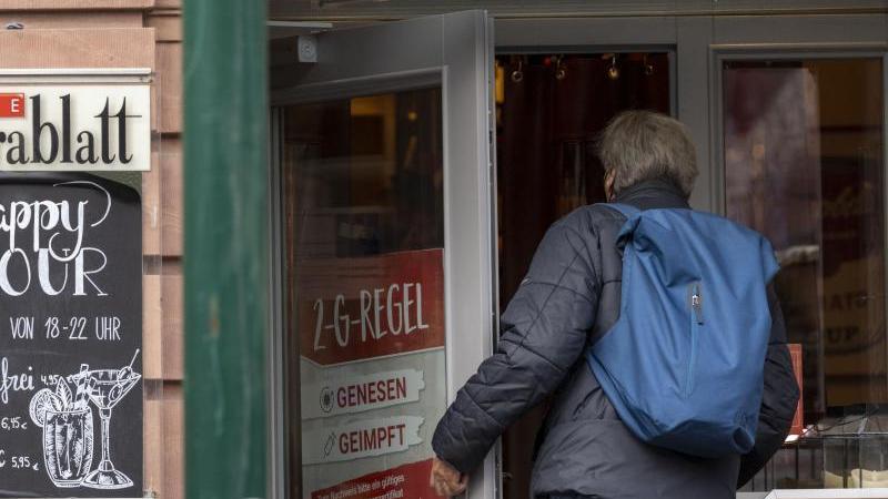 Ein Mann betritt ein Café in der Mainzer Altstadt, an dessen Tür auf die 2-G-Regel hingewiesen wird. Foto: Helmut Fricke/dpa