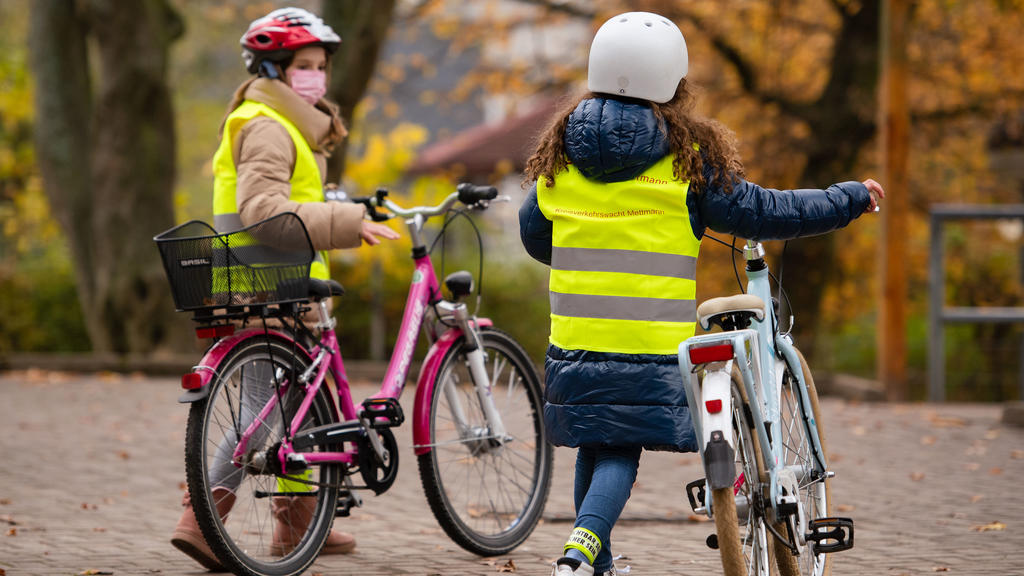 Kinder mit Warnwesten schieben nach einem Pressetermin ihre Fahrräder um den Schulhof. Um die Sichtbarkeit von Kindern auf dem Fahrrad zu verbessern, stellt das Land Nordrhein-Westfalen Speichenreflektoren fü