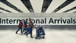 26.11.2021, Großbritannien, London Heathrow: Passagiere gehen mit ihrem Gepäck durch das Ankunftsterminal auf dem Londoner Flughafen Heathrow. Nach der Entdeckung einer neuen Virusvariante gab die Regierung von Großbritannien bekannt, dass es ein Flugverbot für Flüge aus Südafrika und fünf anderen Ländern des südlichen Afrikas verhängt hat und dass alle Personen einen Corona-Test durchführen müssen, die kürzlich aus diesen Ländern eingereist sind. Foto: Alberto Pezzali/AP/dpa +++ dpa-Bildfunk +++