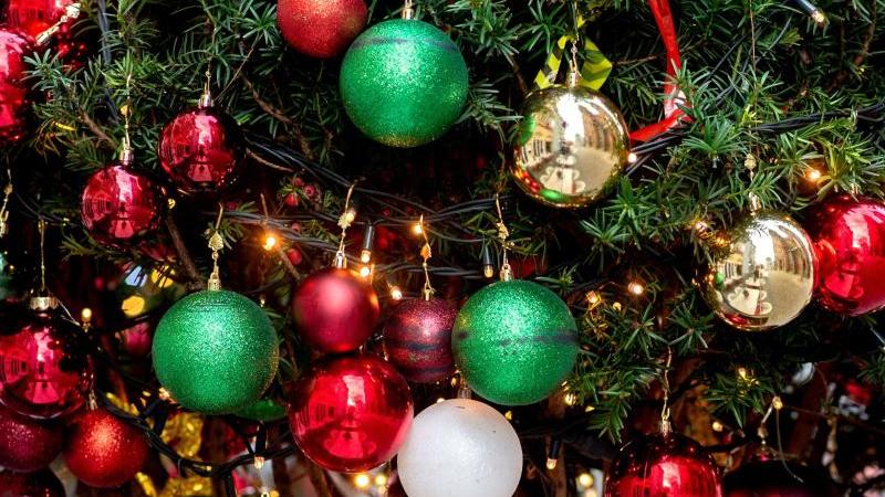 Ein Weihnachtsbaum ist mit zahlreichen Christbaumkugeln und Lichterketten geschmückt. Foto: Hauke-Christian Dittrich/dpa/Archivbild