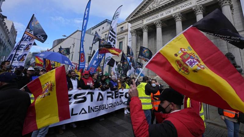Polizisten laufen während des Protestmarsches am spanischen Parlament in Madrid vorbei. Foto: Paul White/AP/dpa