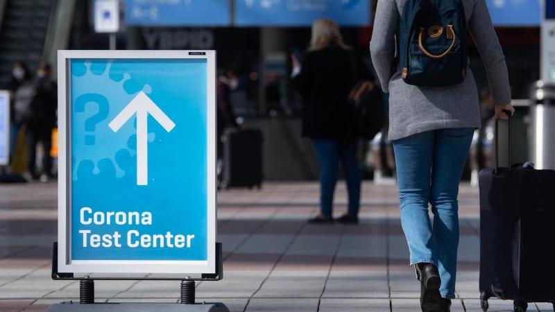 Ein Schild weist auf ein Corona-Testcenter am Flughafen München hin. (Symbolbild). Foto: Sven Hoppe/dpa
