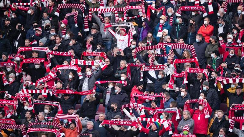 Fans des 1. FC Köln halten Fanschals in die Luft. Foto: Marius Becker/dpa