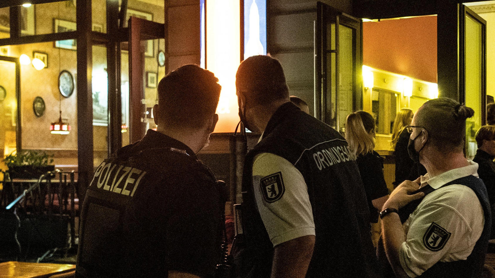 ARCHIV - 24.07.2020, Berlin: Ein Polizeibeamter und zwei Mitarbeiter des Ordnungsamtes stehen vor einem Lokal. Angesichts der verschärften Corona-Regeln hält die Gewerkschaft der Polizei (GdP) eine Impfpflicht für Polizisten erforderlich. (zu dpa «Be