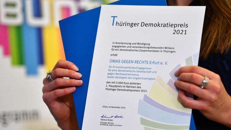 Eine Frau präsentiert die Urkunde für den 1. Hauptpreis für die Omas gegen Rechts Erfurt e. V. Foto: Martin Schutt/dpa-Zentralbild/dpa