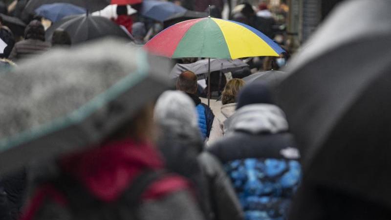 Passanten gehen mit Regenschirmen in der Fußgängerzone in der Innenstadt. Foto: Frank Rumpenhorst/dpa