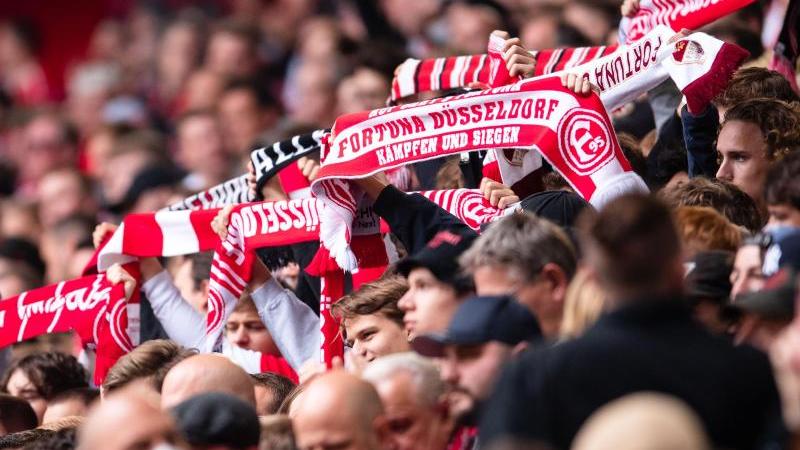 Düsseldorfer Fans halten vor einer Partie ihre Fanschals in die Höhe. Foto: Marius Becker/dpa/Archivbild