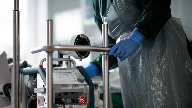 Eine Pflegekraft steht auf einer Intensivstation in einem Zimmer und bedient eine Herz-Lungen-Maschine. Foto: Fabian Strauch/dpa/Symbolbild