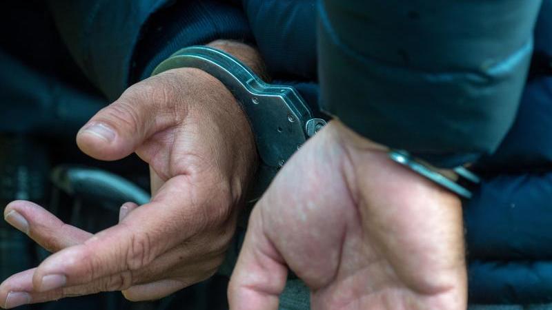 Ein Mann trägt Handschellen. Foto: Stefan Sauer/dpa/Illustration