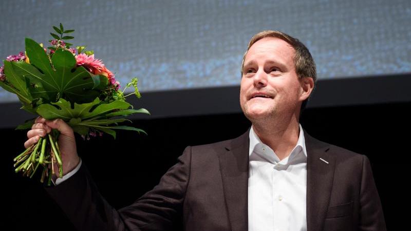Oke Göttlich hält nach seiner Wahl zum Präsidenten einen Blumenstrauß. Foto: Gregor Fischer/dpa