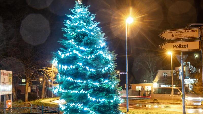 Der beleuchtete Weihnachtsbaum in der Dorfmitte schwankt bei starkem Wind. Foto: Jens Büttner/dpa-Zentralbild/dpa