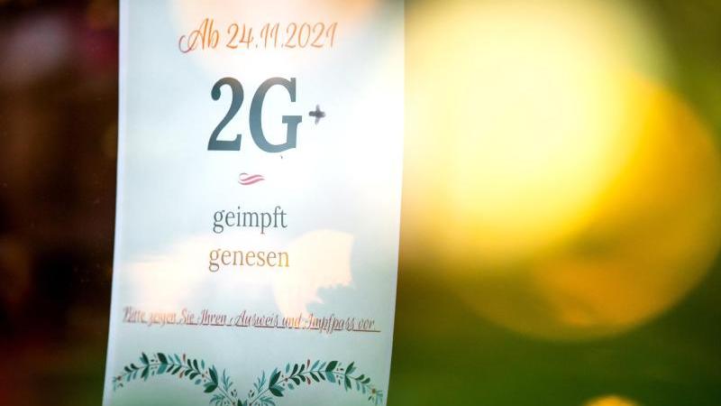 Ein Schild mit der Aufschrift "Ab 24.11.2021 2G, geimpft, genesen" hängt an der Tür eines Cafés. Foto: Sina Schuldt/dpa/Archivbild