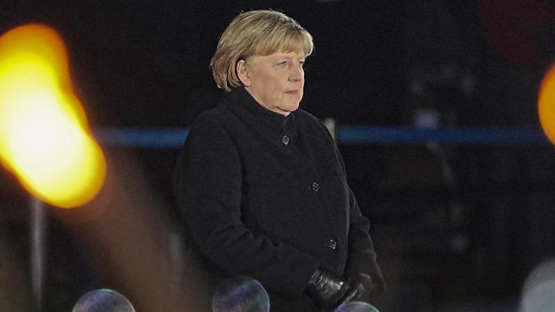 Bundeskanzlerin Angela Merkel (CDU) steht bei ihrer Verabschiedung durch die Bundeswehr auf dem Podium. Foto: Michael Kappeler/dpa