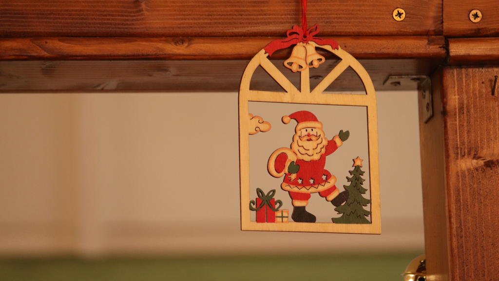 Eine keine Weihnachtsmann-Deko hängt an einem Balken