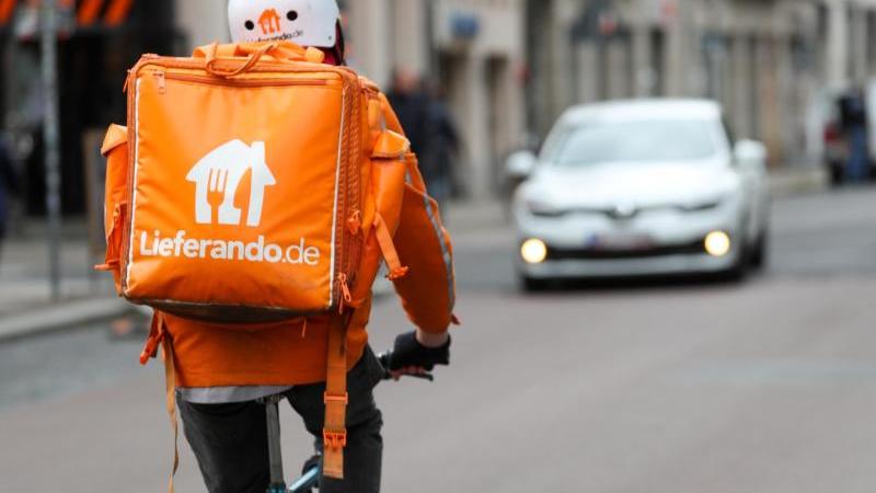 Sie sind von deutschen Straßen kaum noch wegzudenken: Junge Männer und Frauen in orangenen Jacken mit würfelförmigen Rucksäcken auf dem Rad.