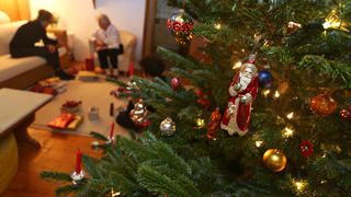 ARCHIV - 24.12.2018, Bayern, Kaufbeuren: Menschen sitzen in einem Wohnzimmer hinter einem geschmückten Christbaum. (zu dpa "Können wir uns auf «Corona-Weihnachten 2.0» freuen?") Foto: Karl-Josef Hildenbrand/dpa +++ dpa-Bildfunk +++