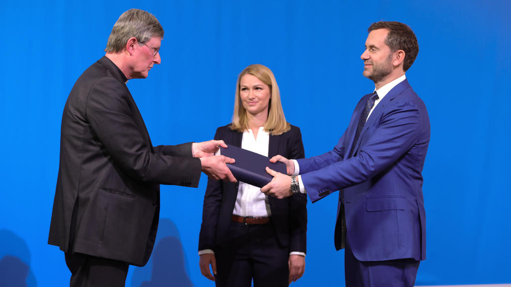 18.03.2021, Nordrhein-Westfalen, Köln: Rechtsanwältin Kerstin Stirner (M) schaut zu, wie der von der Kirche beauftragte Anwalt Björn Gercke (r) dem Kölner Erzbischof Rainer Maria Woelki (l) während einer Pressekonferenz ein Exemplar eines Gutachtens