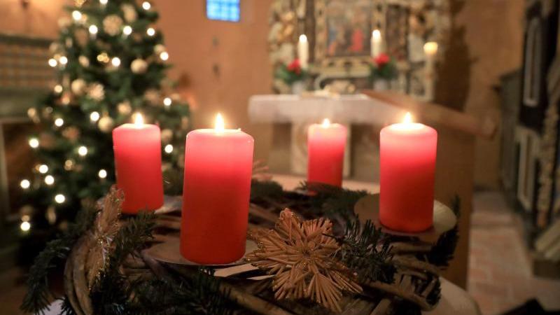 Vier brennende Kerzen auf einem Adventskranz bei einem Weihnachtsgottesdienst