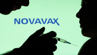 People pose with syringe with needle in front of displayed Novavax logo in this illustration taken, December 11, 2021. REUTERS/Dado Ruvic/Illustration