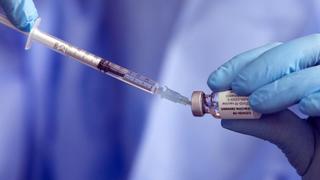 Eine Spritze mit einem Corona-Impfstoff wird aufgezogen