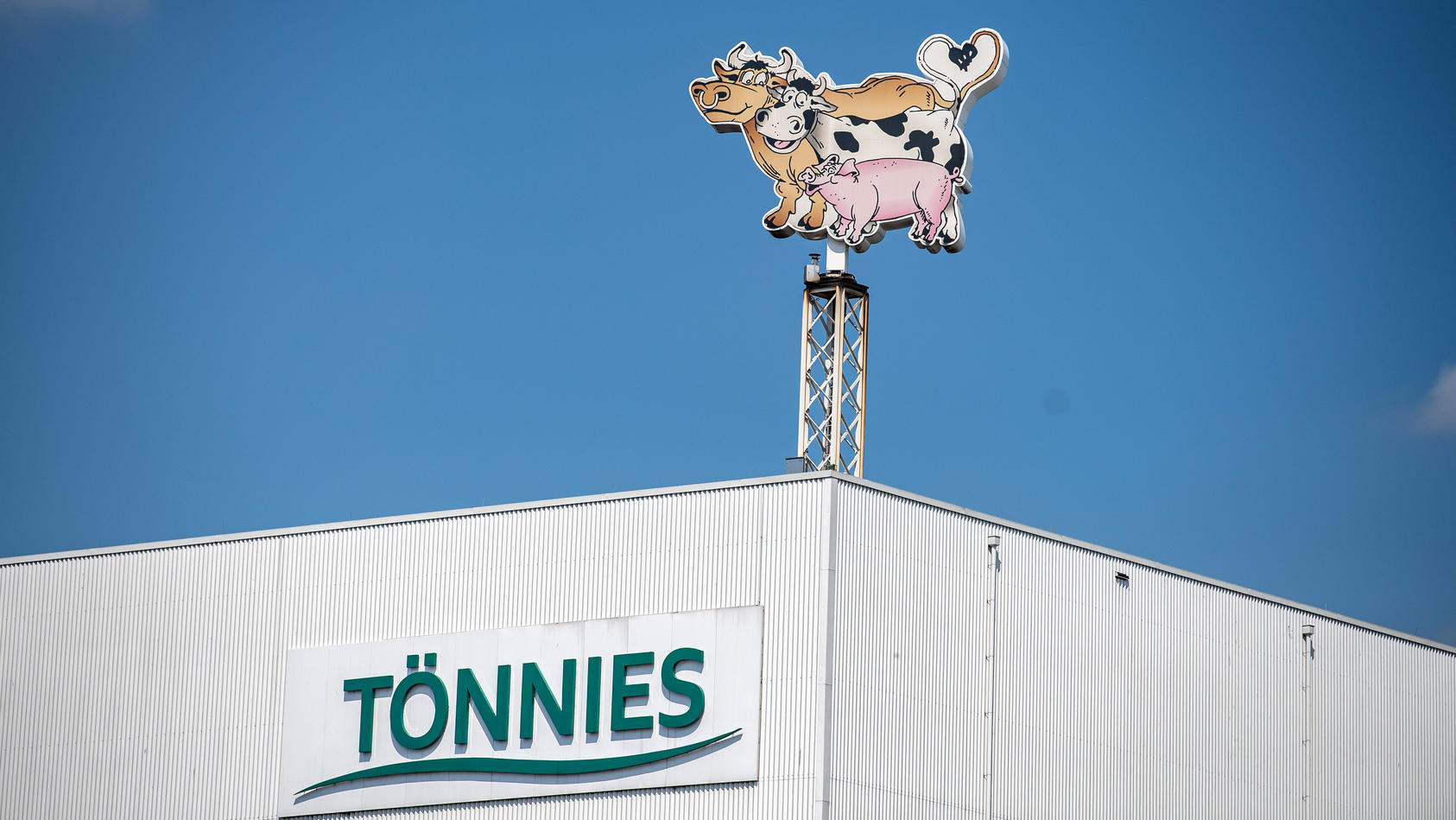 Auf dem Dach des Werksgeländes steht das Logo der Firma Tönnies in Form von zwei Kühen und einem Schwein.