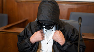 ARCHIV - 04.08.2020, Nordrhein-Westfalen, Dortmund: Der Angeklagte verbirgt auf der Anklagebank im Landgericht sein Gesicht hinter einer Gesichtsmaske, einer Brille und unter einer Kapuze. Der Mann wurde inzwischen rechtskräftig verurteilt, die damals 16-jährige Schülerin Nicole-Denise Schalla ermordet zu haben. Er hat kurz vor Vollstreckung der Haft seine Fußfessel abgelegt und ist verschwunden (zu dpa: «Verurteilter Mörder legt vor Haft Fußfessel ab - Polizei fahndet») Foto: Bernd Thissen/dpa +++ dpa-Bildfunk +++