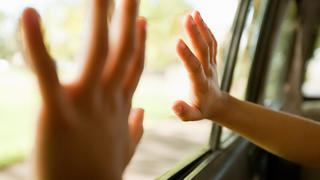 Kinderhände berühren ein Autofenster.