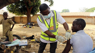 ARCHIV - 06.12.2021, Nigeria, Sabon Kuje: Yunusa Bawa (M), ein kommunaler Gesundheitshelfer, verabreicht einem Mann den Corona-Impfstoff von AstraZeneca in Sabon Kuje am Rande von Abuja. Dutzende Länder vor allem in Afrika werden das Ziel von 40 Prozent Corona-Geimpften bis Ende dieses Jahres verfehlen. Dieses Ziel hatte die Weltgesundheitsorganisation (WHO) im Sommer ausgegeben. Foto: Gbemiga Olamikan/AP/dpa +++ dpa-Bildfunk +++