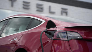 FILE - A 2021 Model 3 sedan charges at a Tesla dealership in Littleton, Colo., on June 27, 2021. Electric vehicle sales nearly doubled in the U.S. and worldwide in 2021. (AP Photo/David Zalubowski, File)
