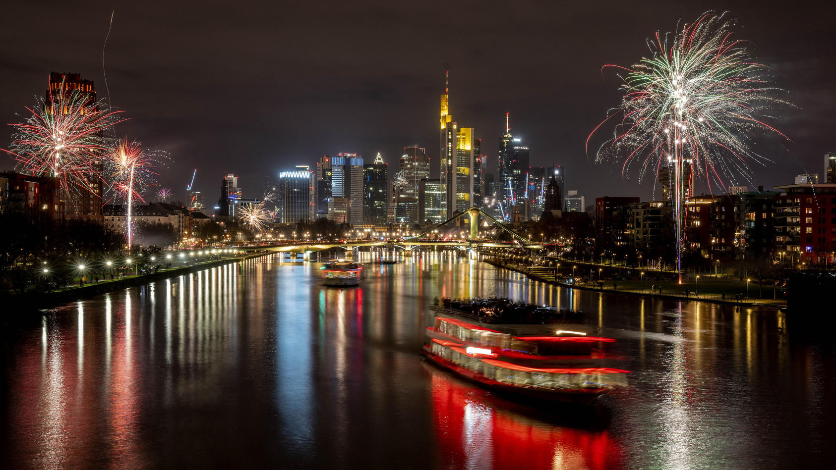 Party boats cruise over the river Main with only a few fireworks near the buildings of the banking district in Frankfurt, Germany, early Saturday, Jan. 1, 2022. Due to the coronavirus pandemic fireworks were not allowed. (Photo/Michael Probst)