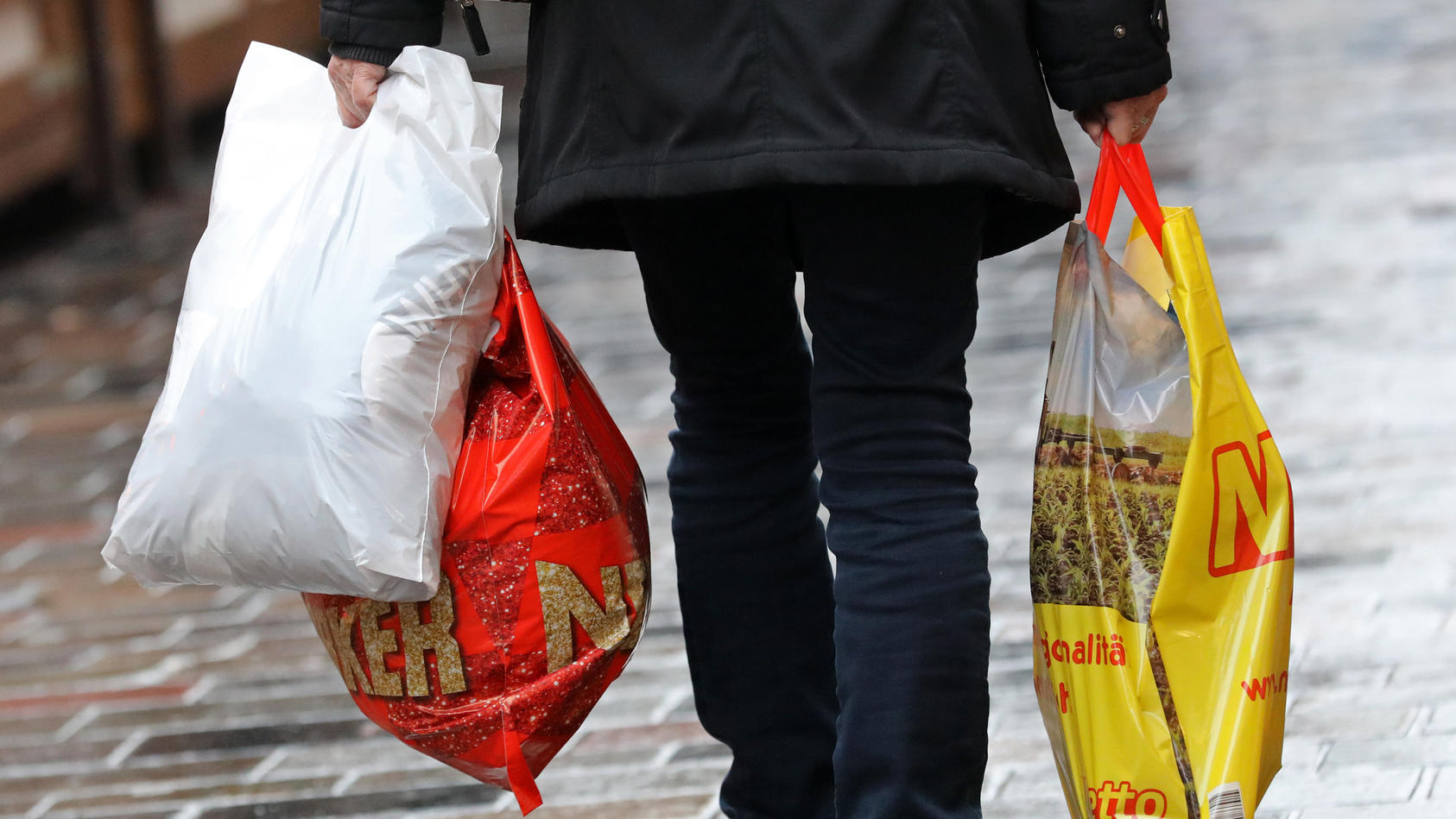ARCHIV - 20.12.2018, Mecklenburg-Vorpommern, Rostock: Eine Frau geht mit Einkaufstüten aus Plastik über den Fußweg. Leichte Plastiktüten dürfen in Deutschland ab 2022 nicht mehr ausgegeben werden. Ab dem 1. Januar dürfen an den deutschen Ladenkassen 