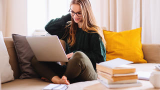 Frau benutzt Laptop auf Sofa