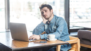 Ein Mann sitzt mit traurigem Gesicht vor einem Laptop