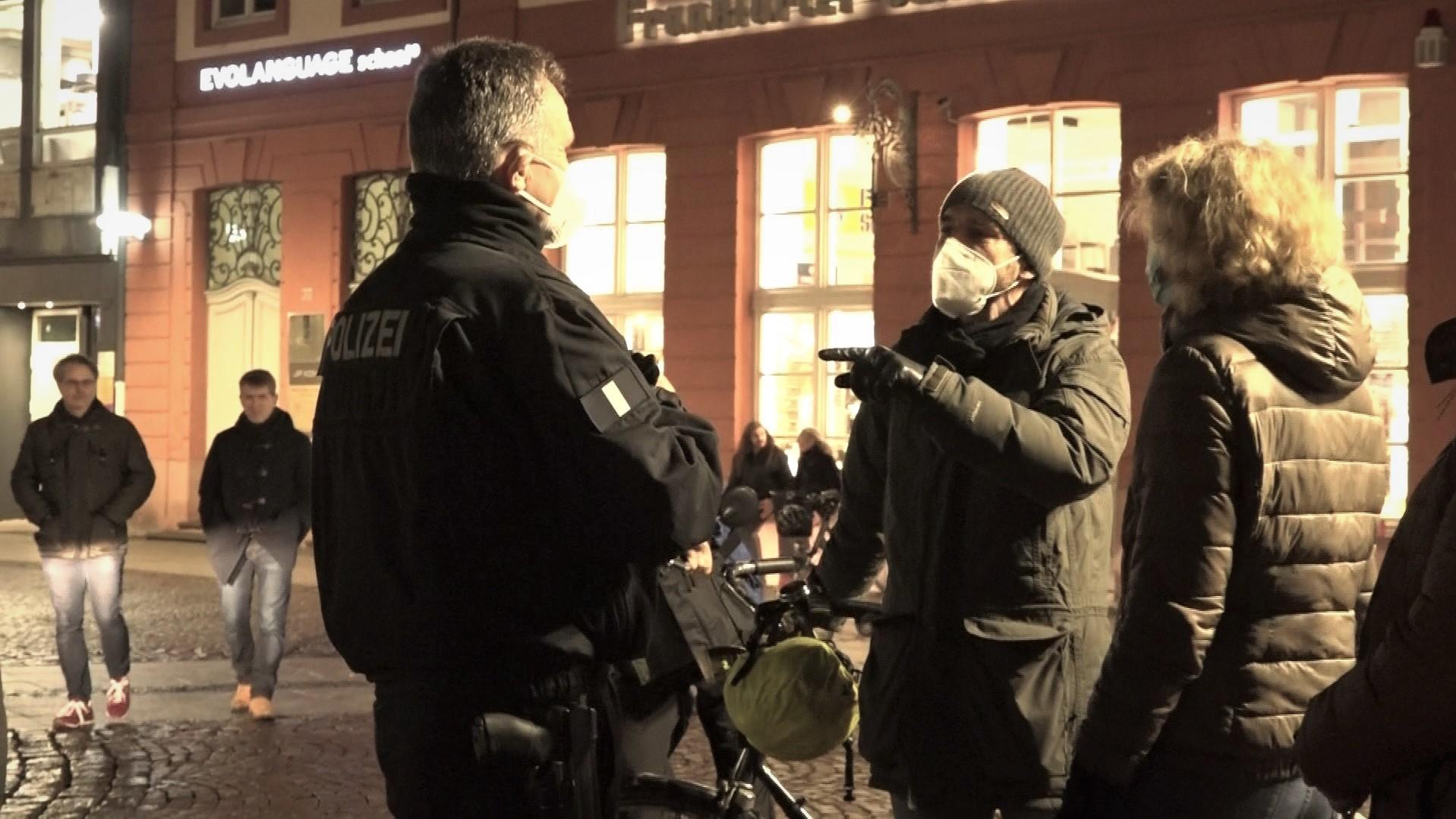 Diskussion mit "Spaziergängern": Ein Polizist im Gespräch mit Demonstranten in Frankfurt.