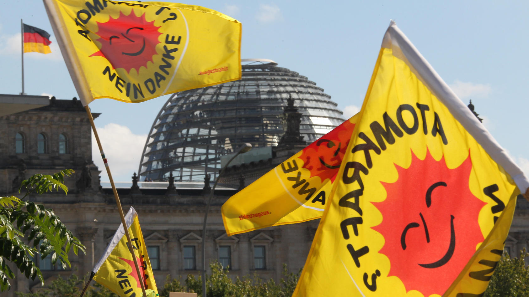 Fahnen von Atomkraft-Gegnern, die am Kanzleramt in Berlin gegen die Atompolitik der Bunderegierung demonstrieren, wehen am Sonntag (05.09.2010) vor der Kuppel des Reichstages. Die Spitzen der Koalition unter Leitung von Bundeskanzlerin Merkel treffen
