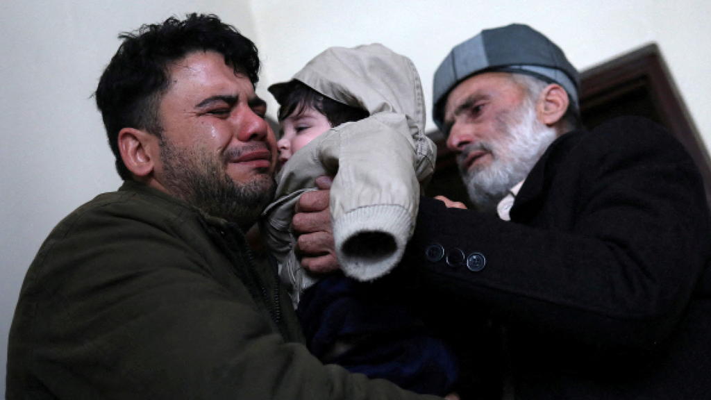 Hamid Safi, a 29-year-old taxi driver who had found baby Sohail Ahmadi in the airport, cries as he hands over Sohail to his grandfather Mohammad Qasem Razawi in Kabul, Afghanistan, January 8, 2022. Picture taken January 8, 2022. REUTERS/Ali Khara