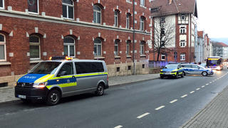 11.01.2022, Thüringen, Jena: Polizeifahrzeuge stehen vor einem Haus. Nach vermeintlichen Schüssen aus einem Luftgewehr auf Passanten ist die Polizei im Einsatz. Die Beamten klärten im Moment vor Ort, von wo aus die Schüsse hätten abgegeben werden können, sagte ein Sprecher der Landeseinsatzzentrale am Dienstag. Derzeit deute alles auf ein Luftgewehr hin. Zu möglichen Verletzten machte er vorerst keine Angaben. Es gebe aber keinen größeren Grund zur Besorgnis. Spezialkräfte, wie es in sozialen Medien berichtet worden war, seien nicht im Einsatz. Foto: David Hutzler/dpa +++ dpa-Bildfunk +++